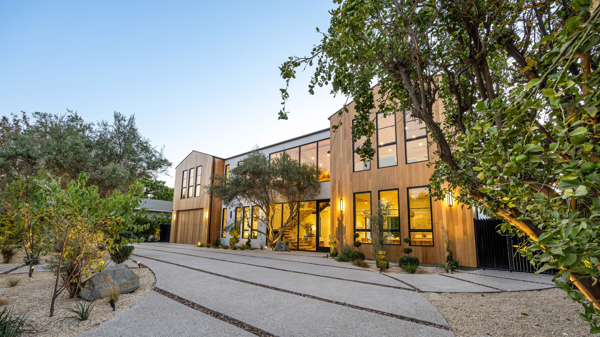 Modern luxury home exterior at twilight with warm interior glow