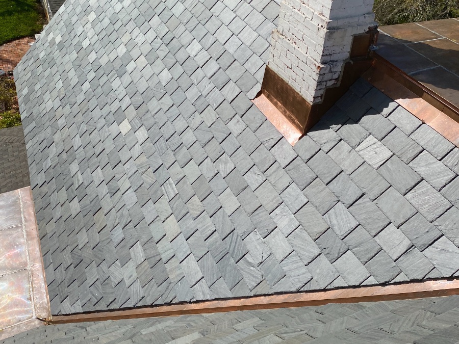 Diagonal slate roof with custom copper valley and chimney flashing